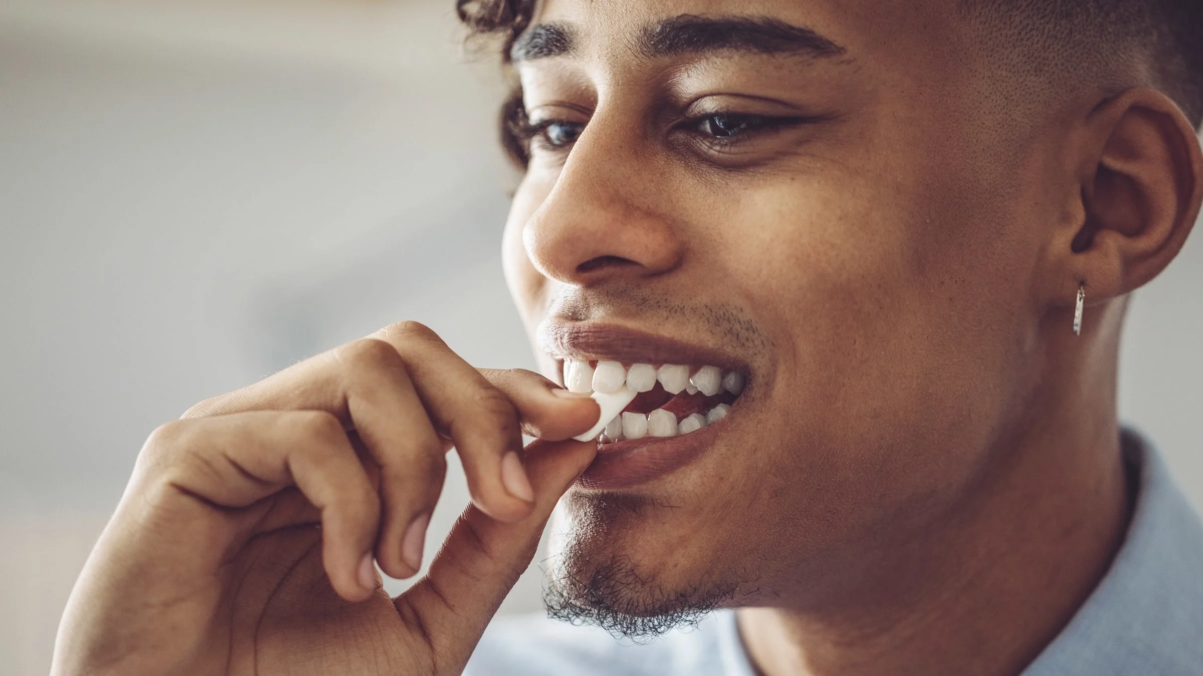 A close-up of a person putting a piece of gum in their mouth.