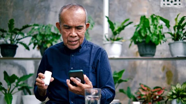 Medication Education: Pharmacy: man researching medication on smart phone 1426188001