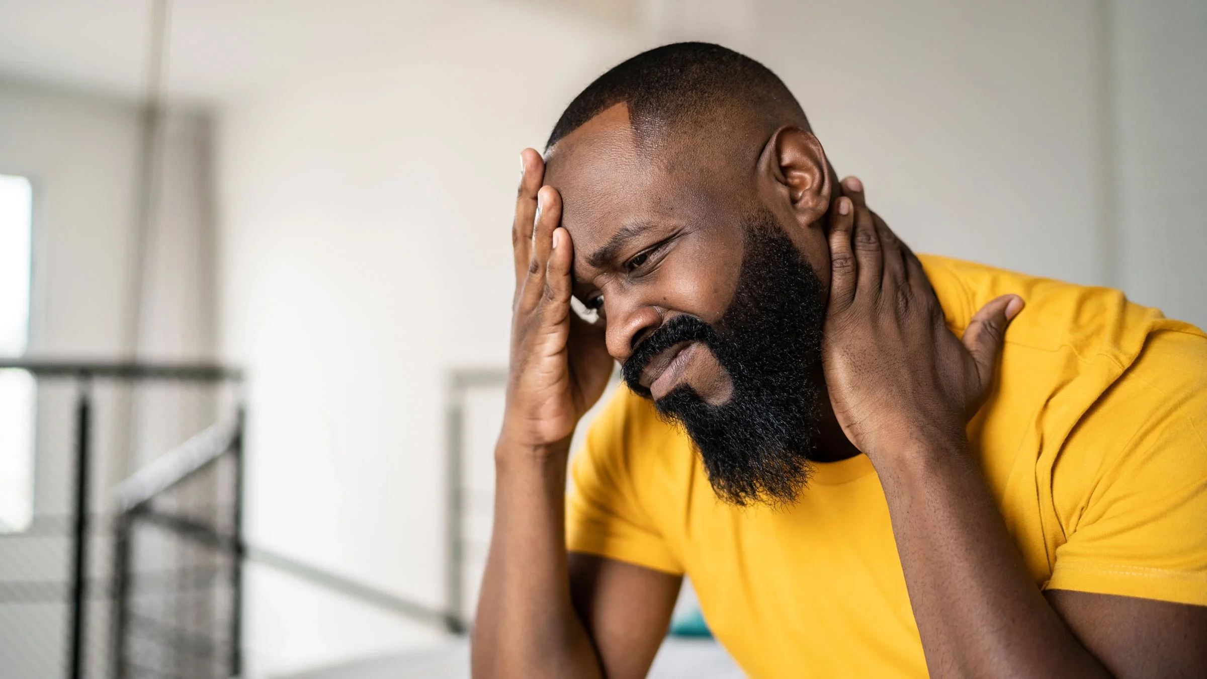 Man with headache and neck pain at home