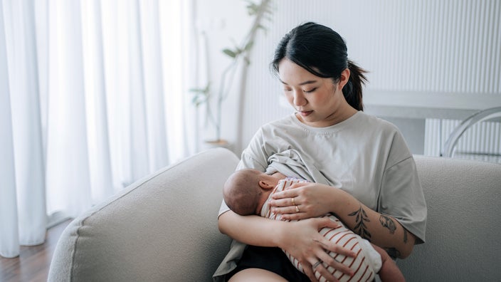 Mother breastfeeding baby at home.