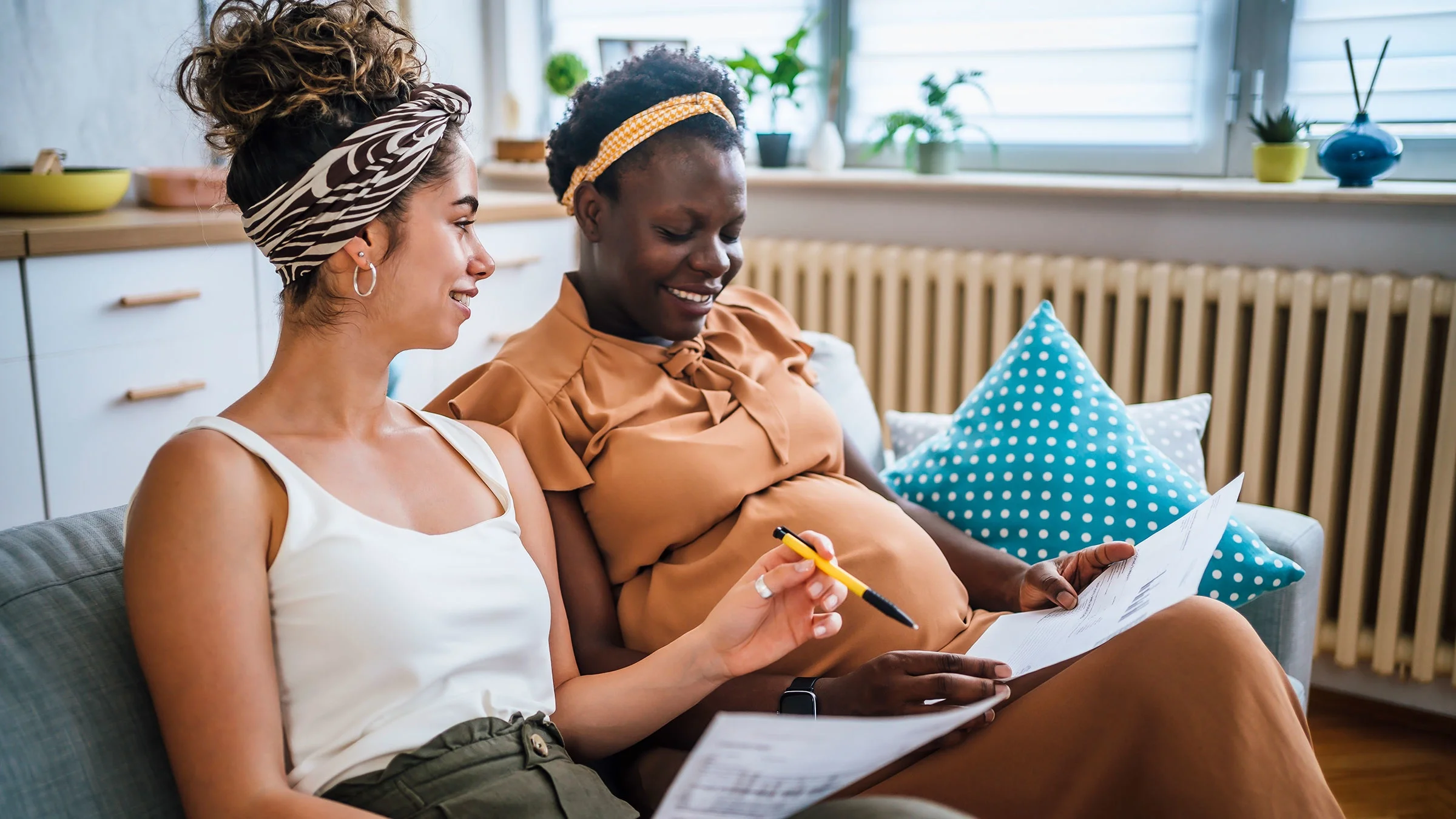 A couple preparing to have a baby is reviewing financial paperwork at home.