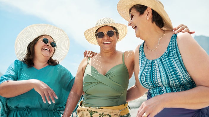 Three friends enjoying a sunny day on the beach. They are each wearing beach straw hats and look really cute and fashionable.
