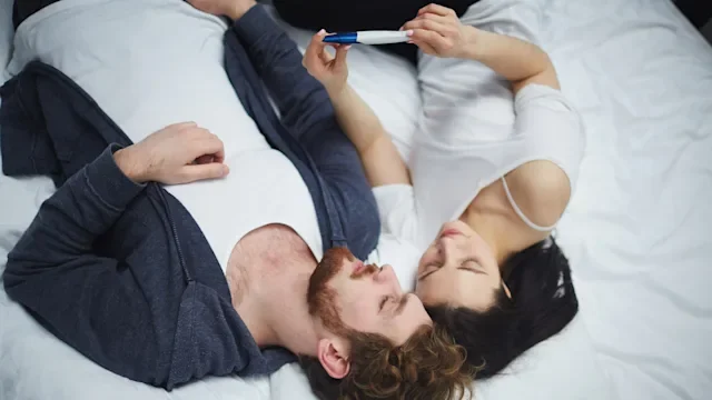 Women's health: Pregnant during period: Pregnancy test: couple in bed with pregnancy test-668575910