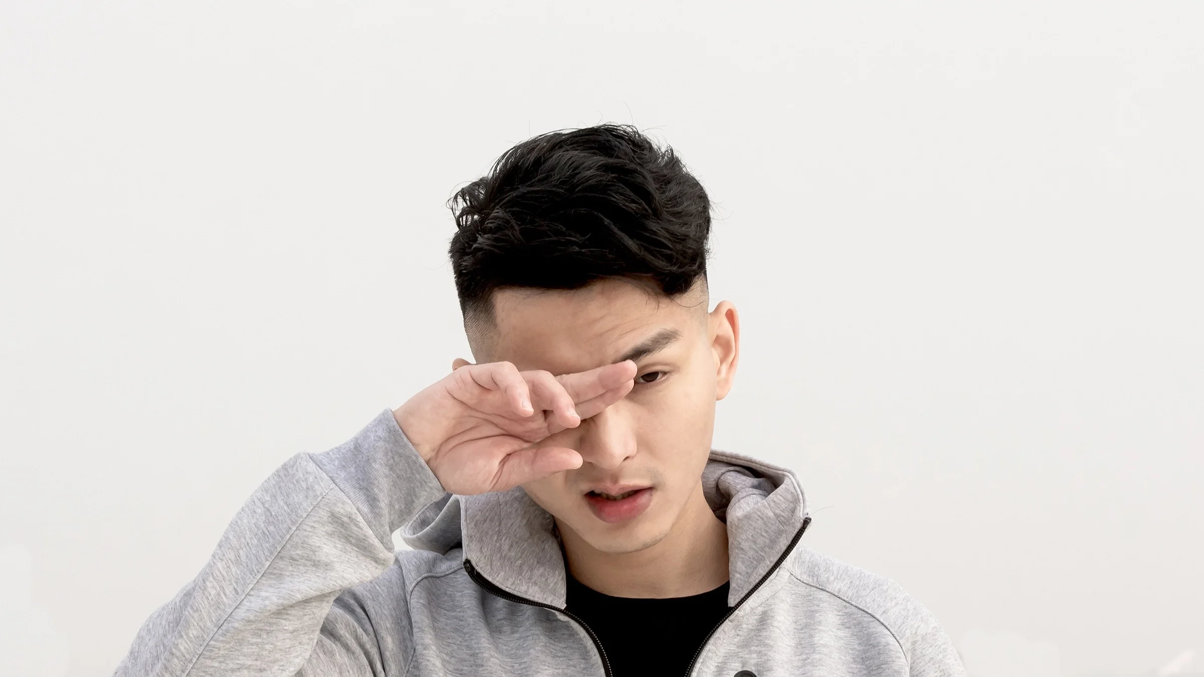 Portrait of a young man itching his eyes on a white studio background.