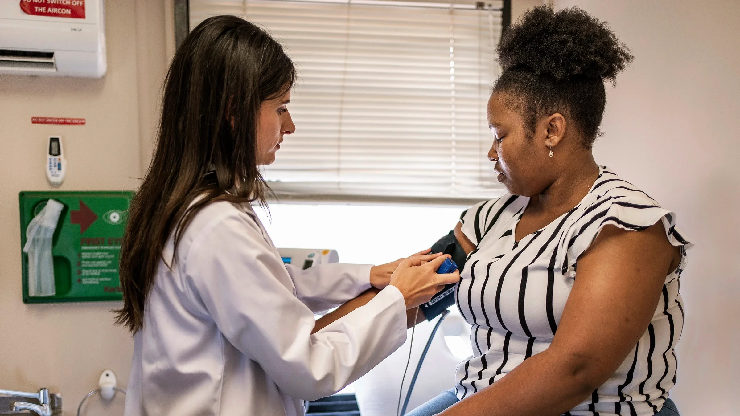A healthcare professional takes a blood pressure reading from a woman. 