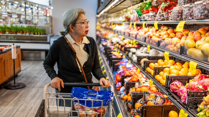 A woman shops for fruit in the produce aisle.