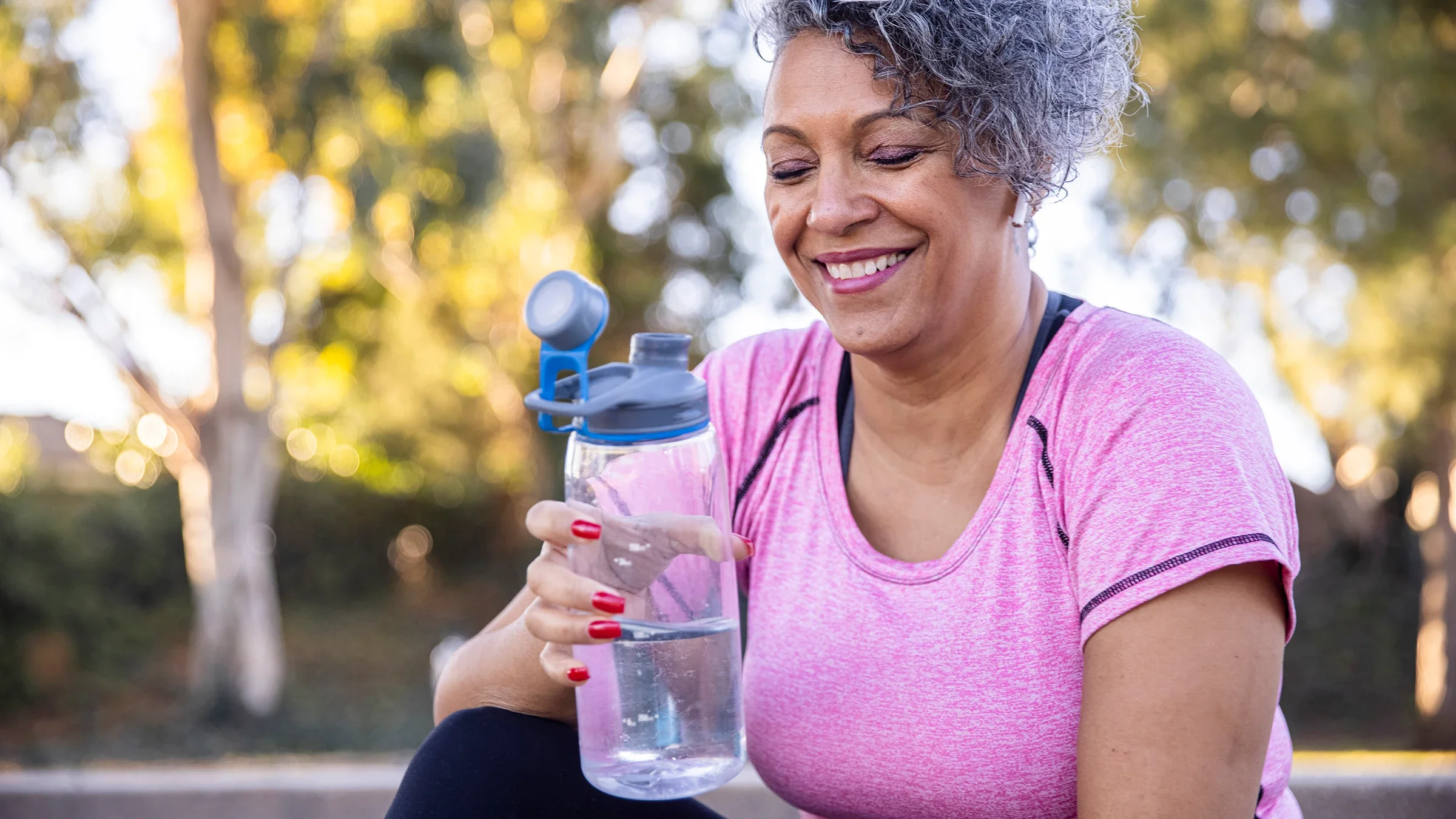 Senior woman drinking water outside after working out.
adamkaz/E+ via Getty Images