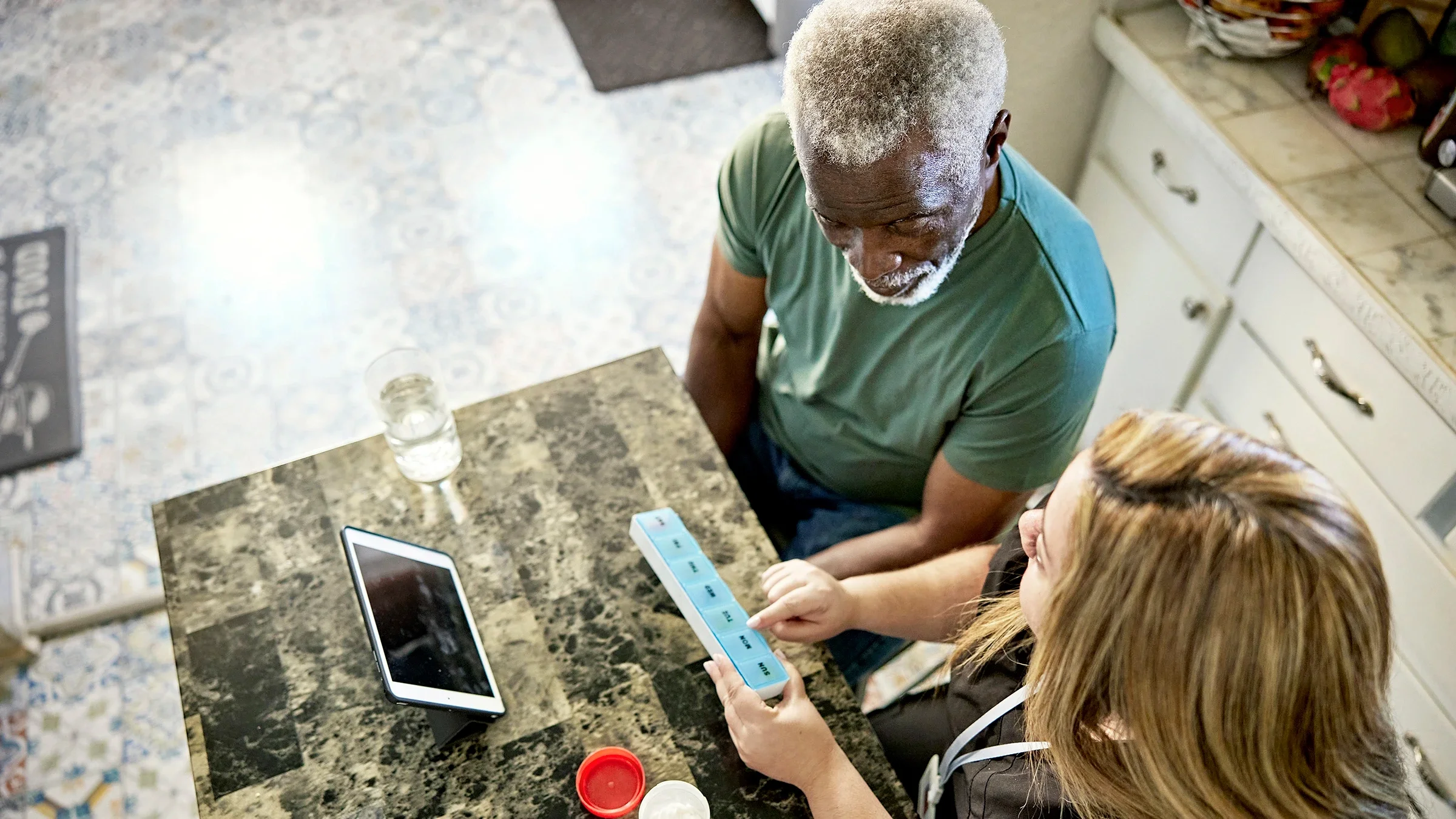 A caregiver shows a client how to organize medication.