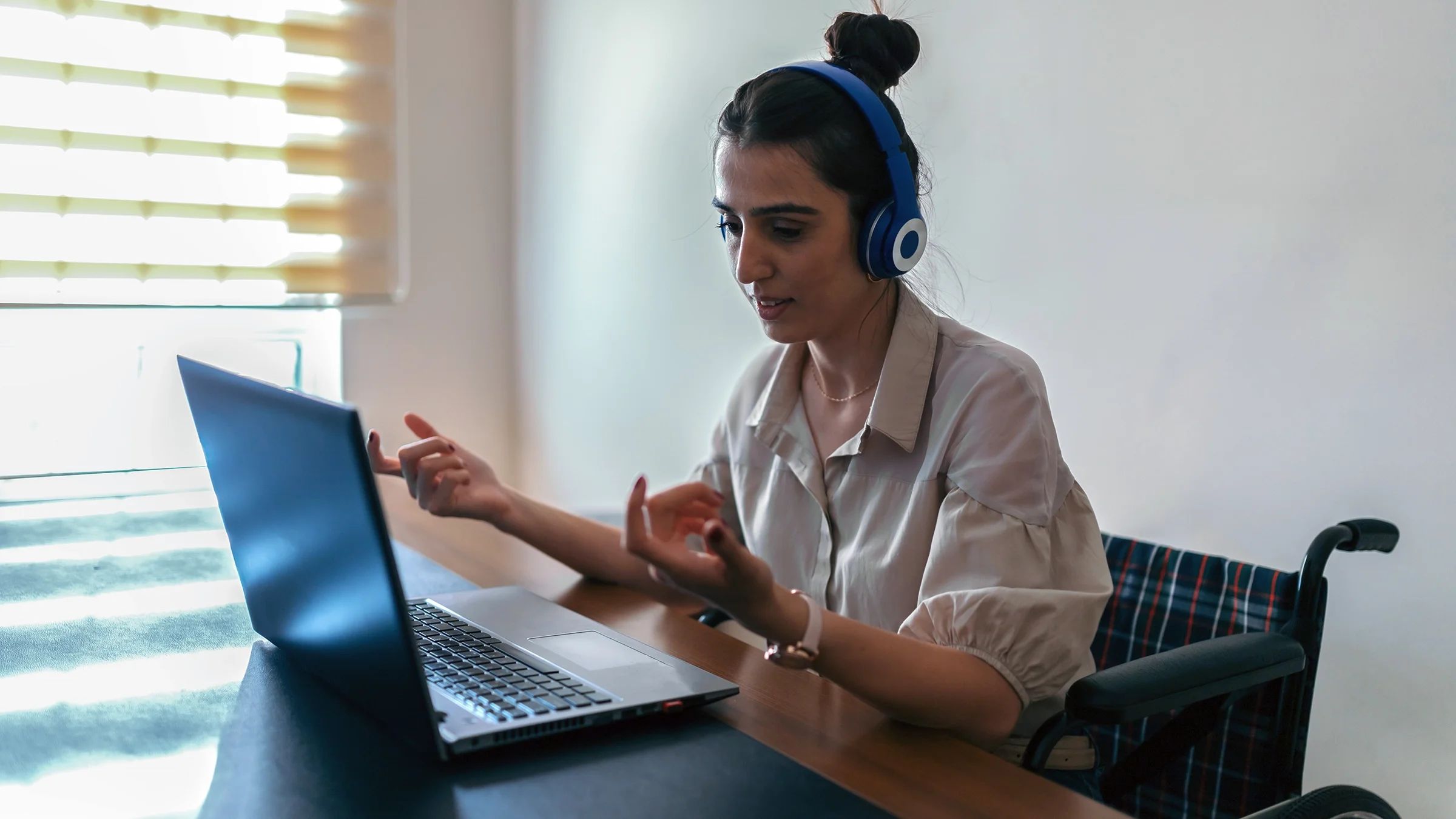 A woman in a wheelchair is on a video call with her therapist.