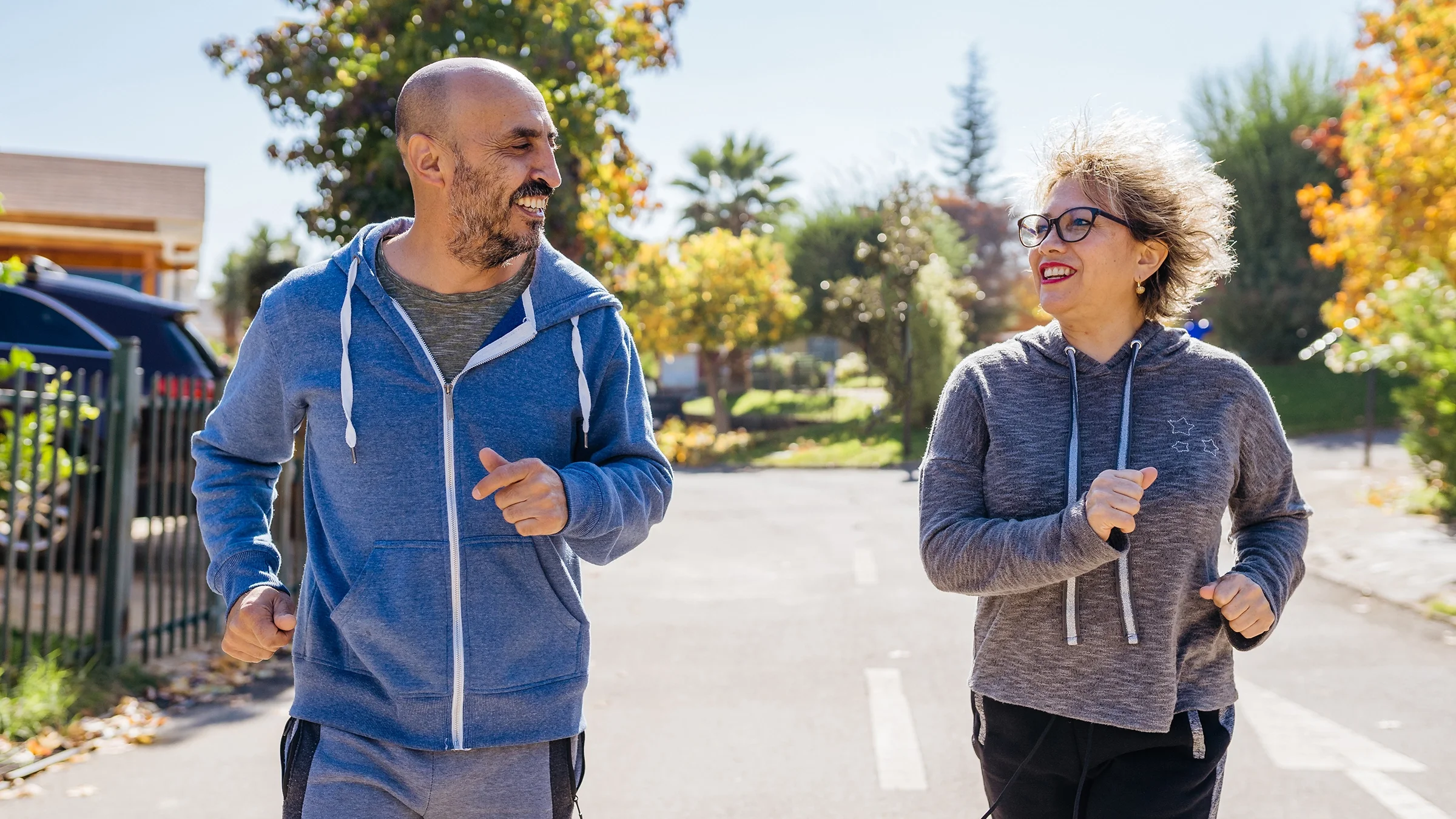 A man and a woman jogging outside on a sunny day.