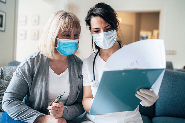 Nurse going over paperwork on a clipboard with an older female patient.