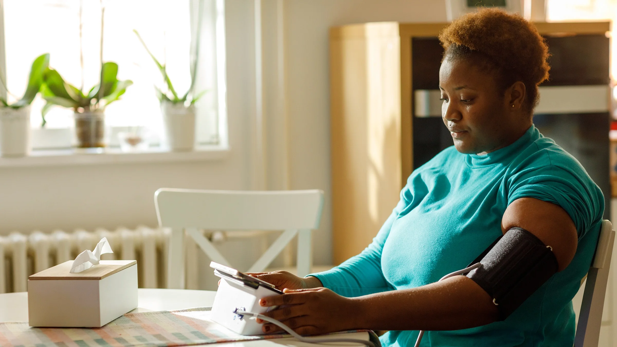 A woman checks her blood pressure at home.