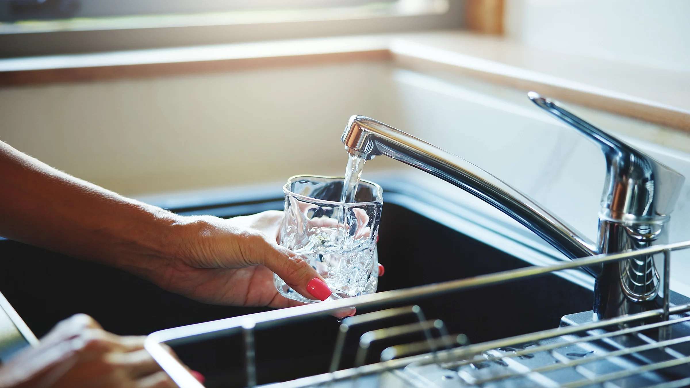 Close-up filling up a glass with water from a kitchen faucet