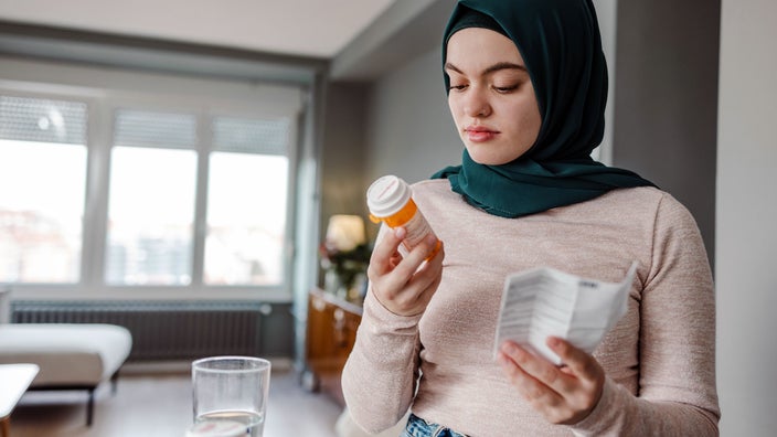A woman reads the the label of her medication bottle.