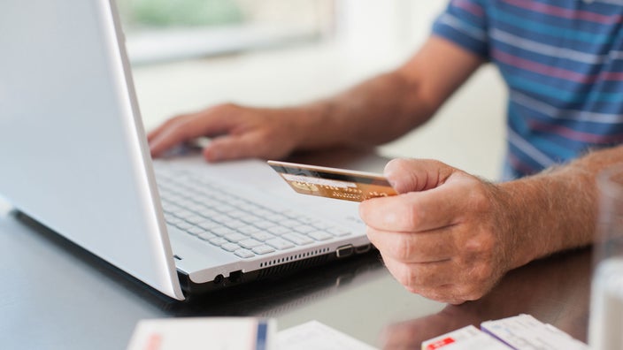 A close-up of a man using a credit card in front of a laptop.