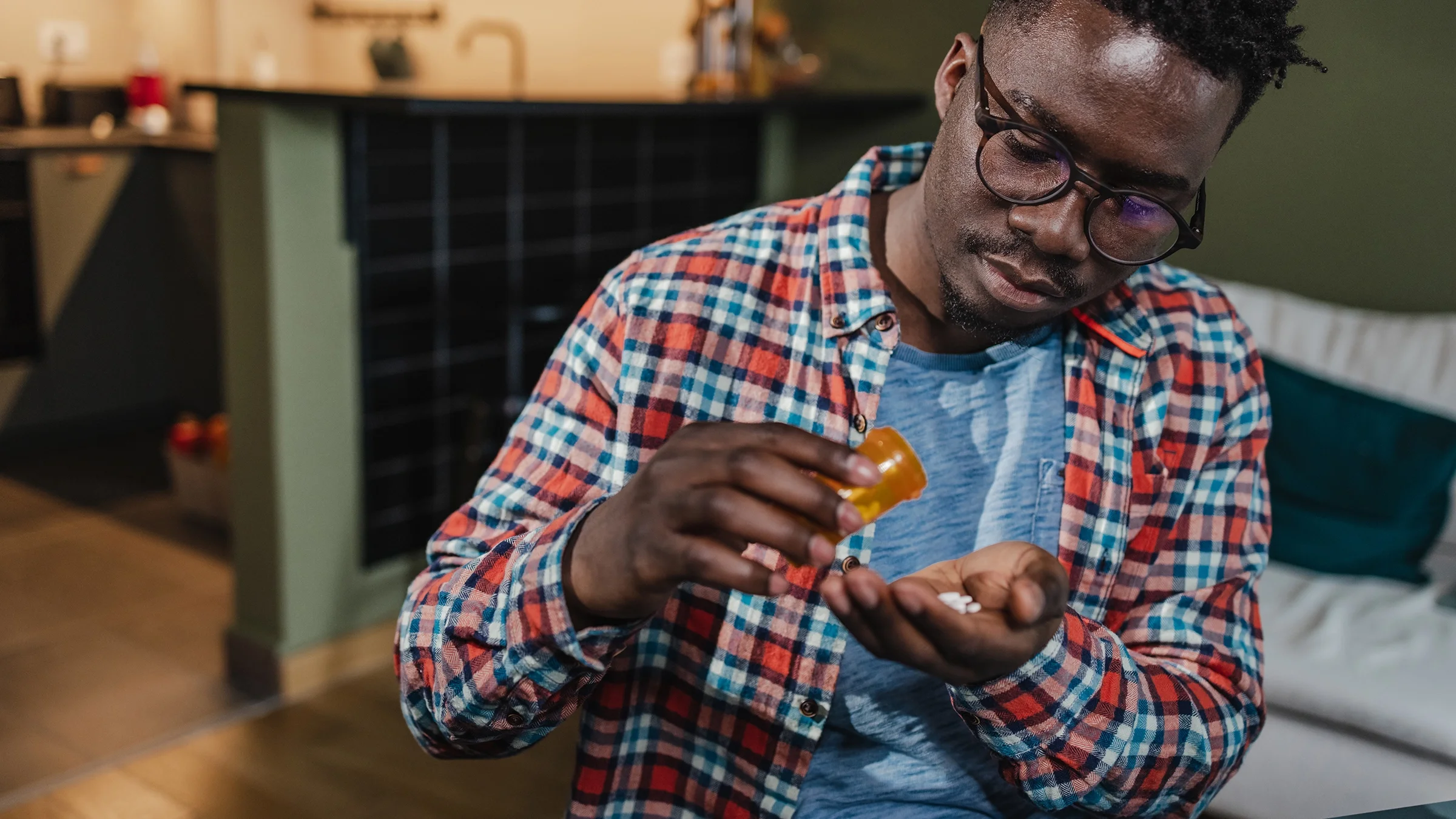 Man taking medicine from orange prescription bottle.