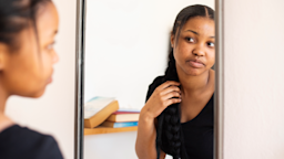 Young woman looking at her face in the mirror.
NickyLloyd/E+ via Getty Images