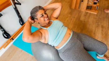 glp-1 agonists: woman doing crunches on exercise ball 2183839074