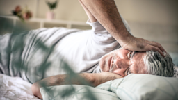 An older man lies in bed while suffering from a headache.
Mladen Zivkovic/E+ via Getty Images