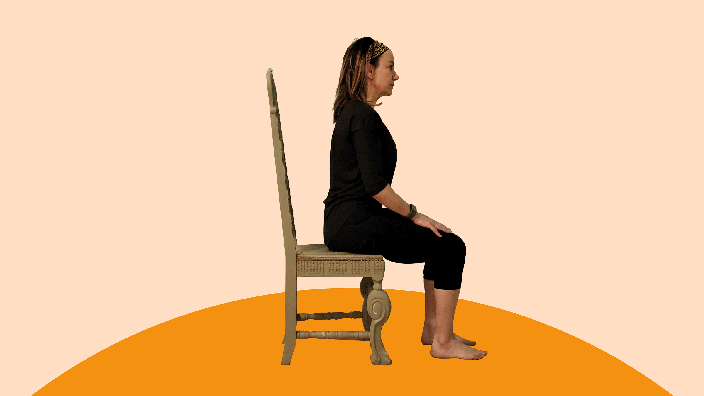 A woman does calf raises exercises on a chair. 