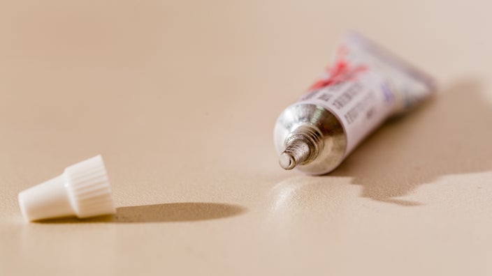 A tube of topical medication is pictured against a beige background.