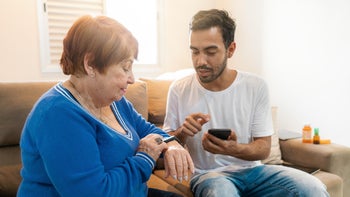 Senior health: son teaching elder how to use smart watch 1423738013