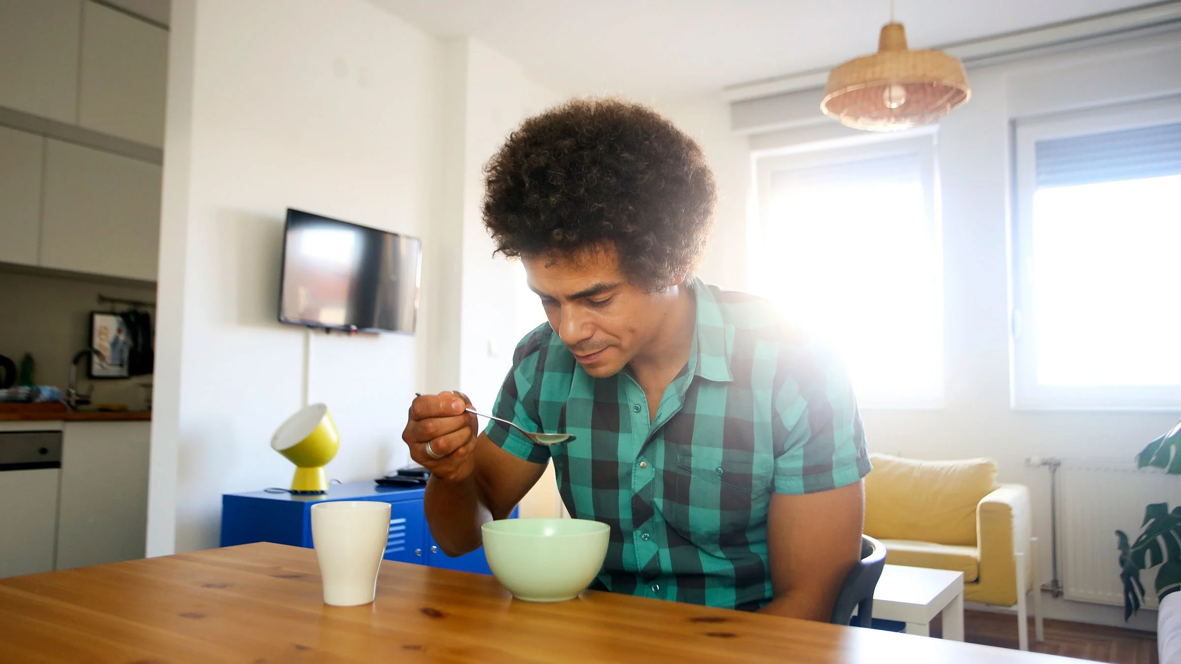 A man eats a bowl of soup at home.