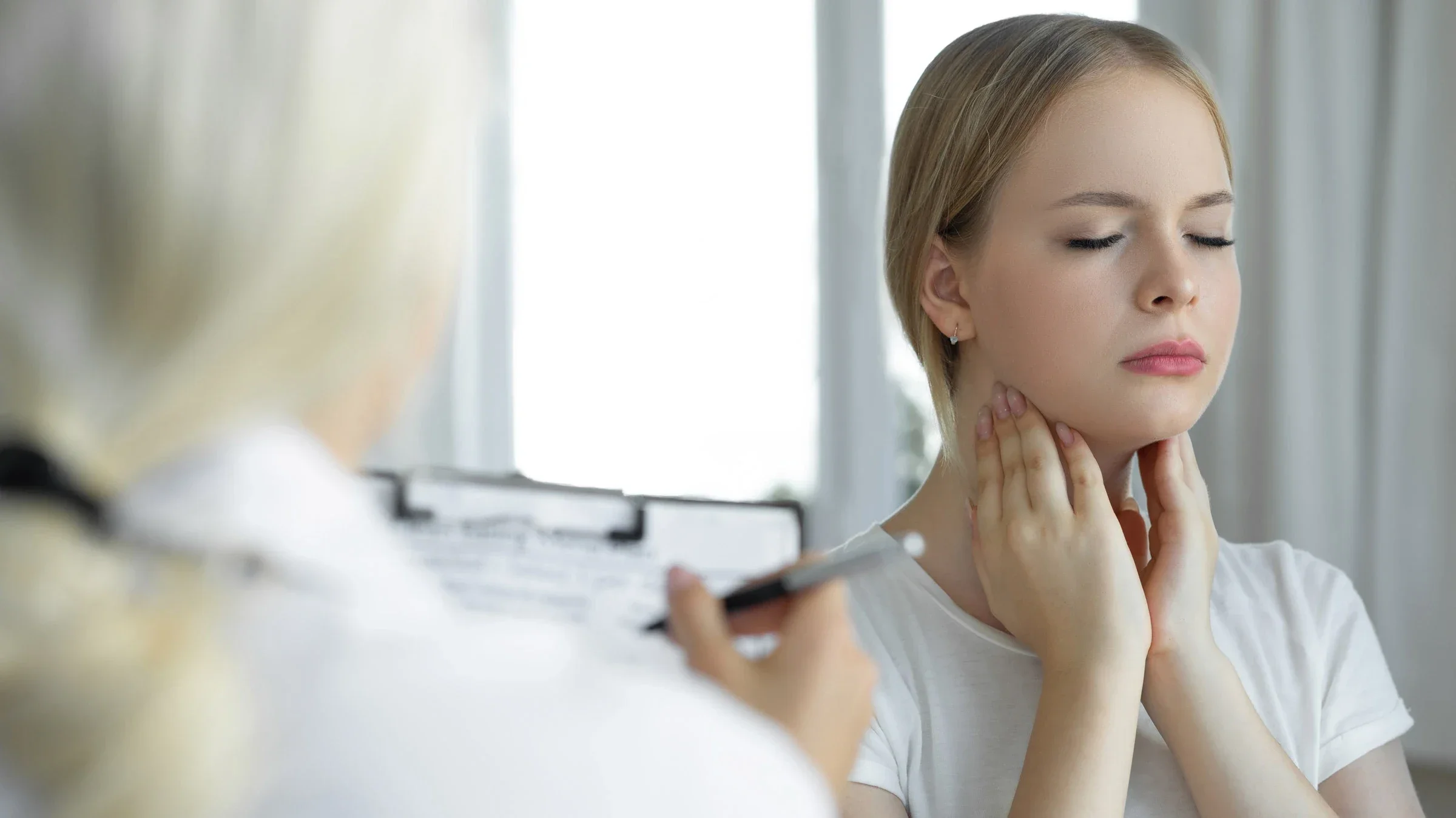 A patient touching their tonsils, while a doctor takes notes.
bymuratdeniz/E+ via Getty Images 