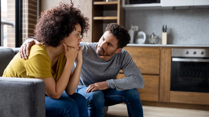 A man comforts his girlfriend at home.