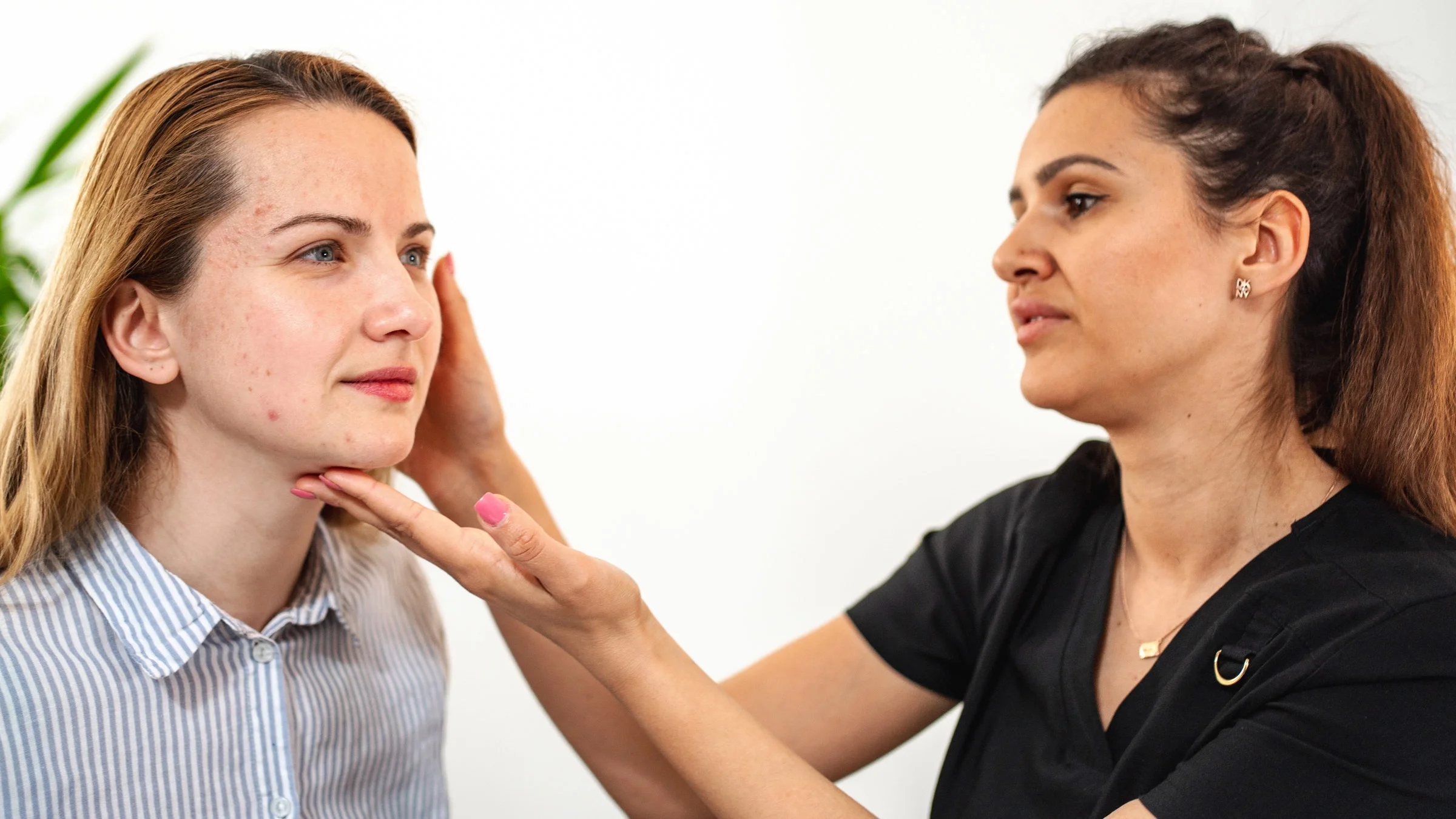 A dermatologist exxamining a patient's face.