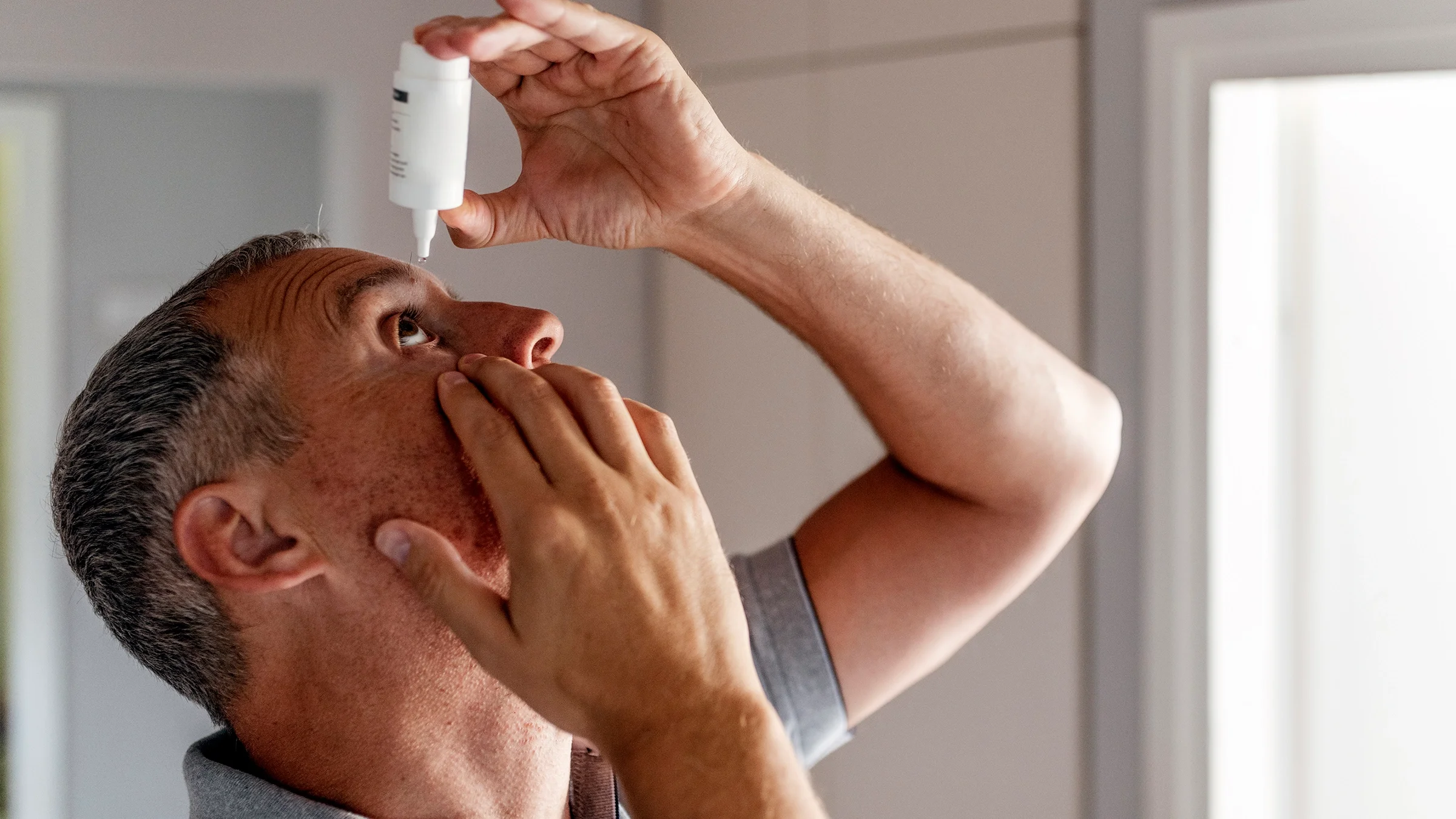 Man tilting his head back to use eye drops.