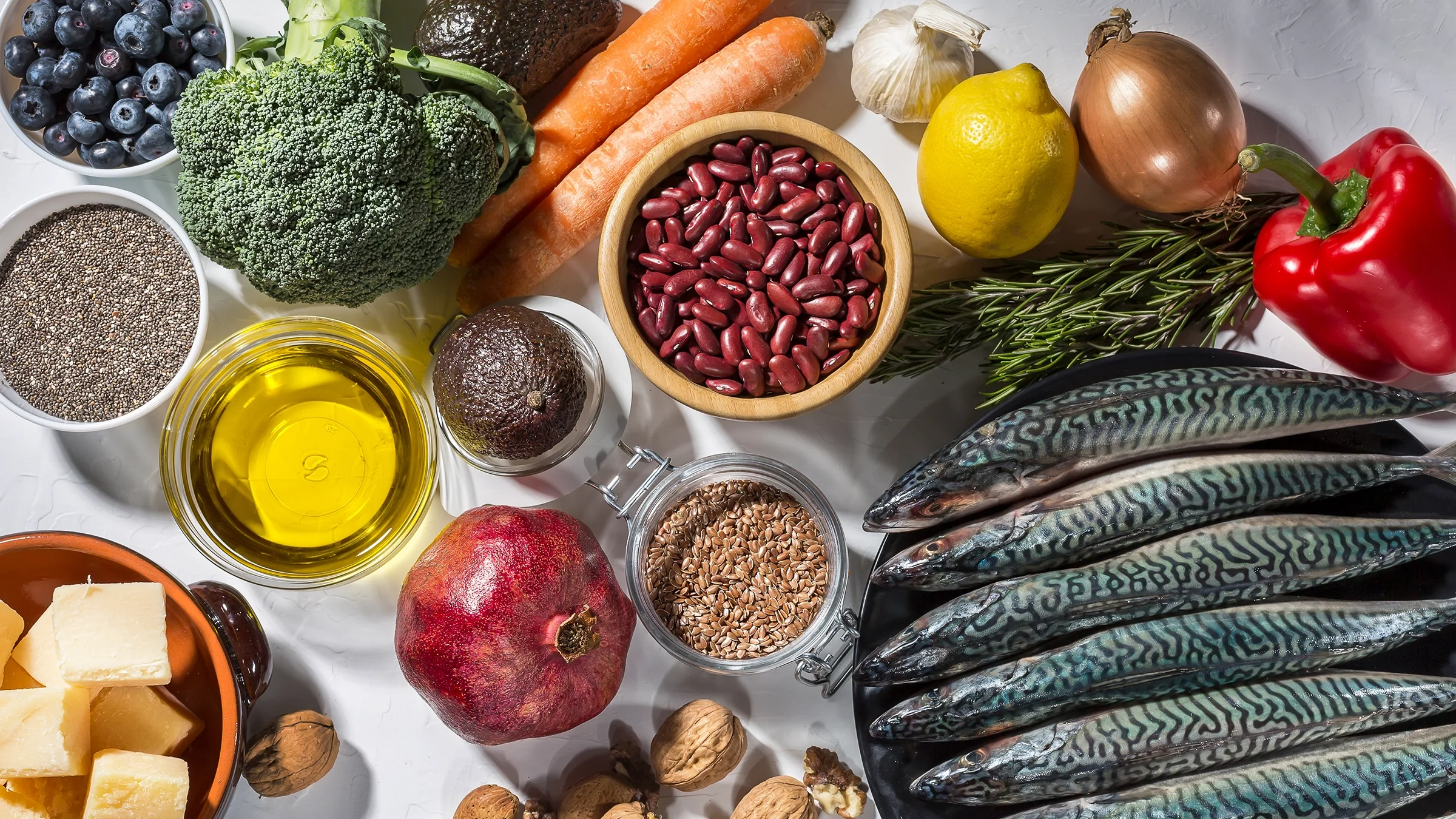 A plethora of healthful foods, such as fish, nuts, seeds, and vegetables, are displayed on a table.