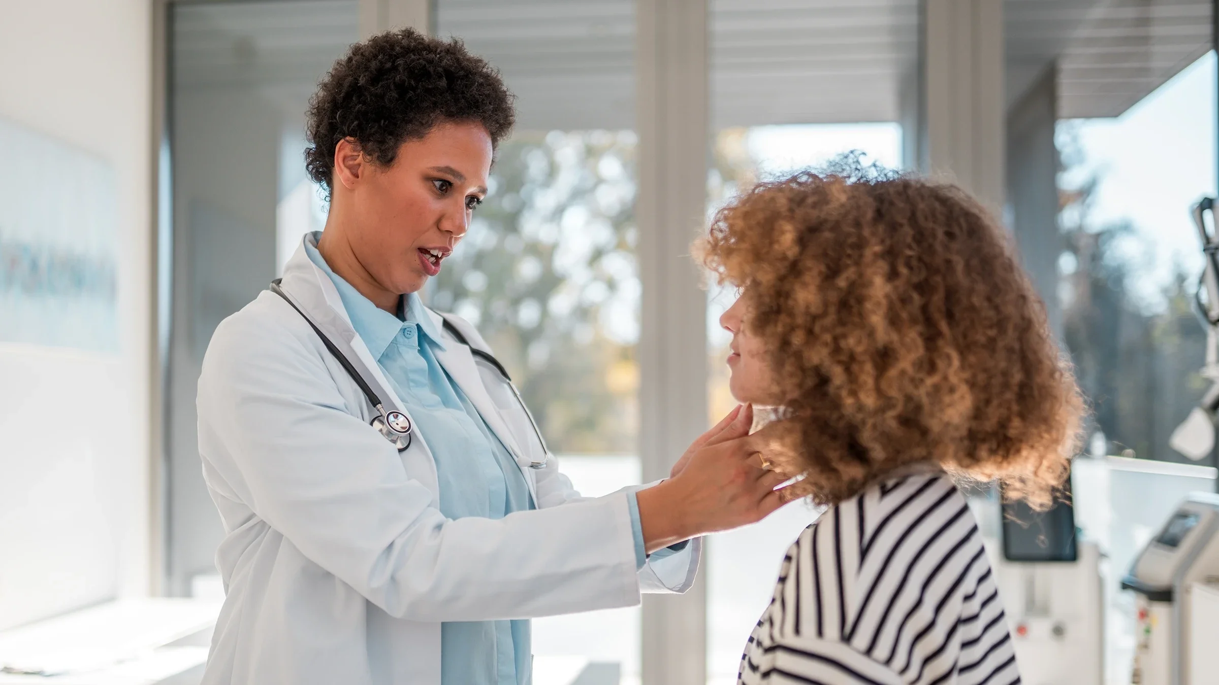 Healthcare professional checking patient’s thyroid.