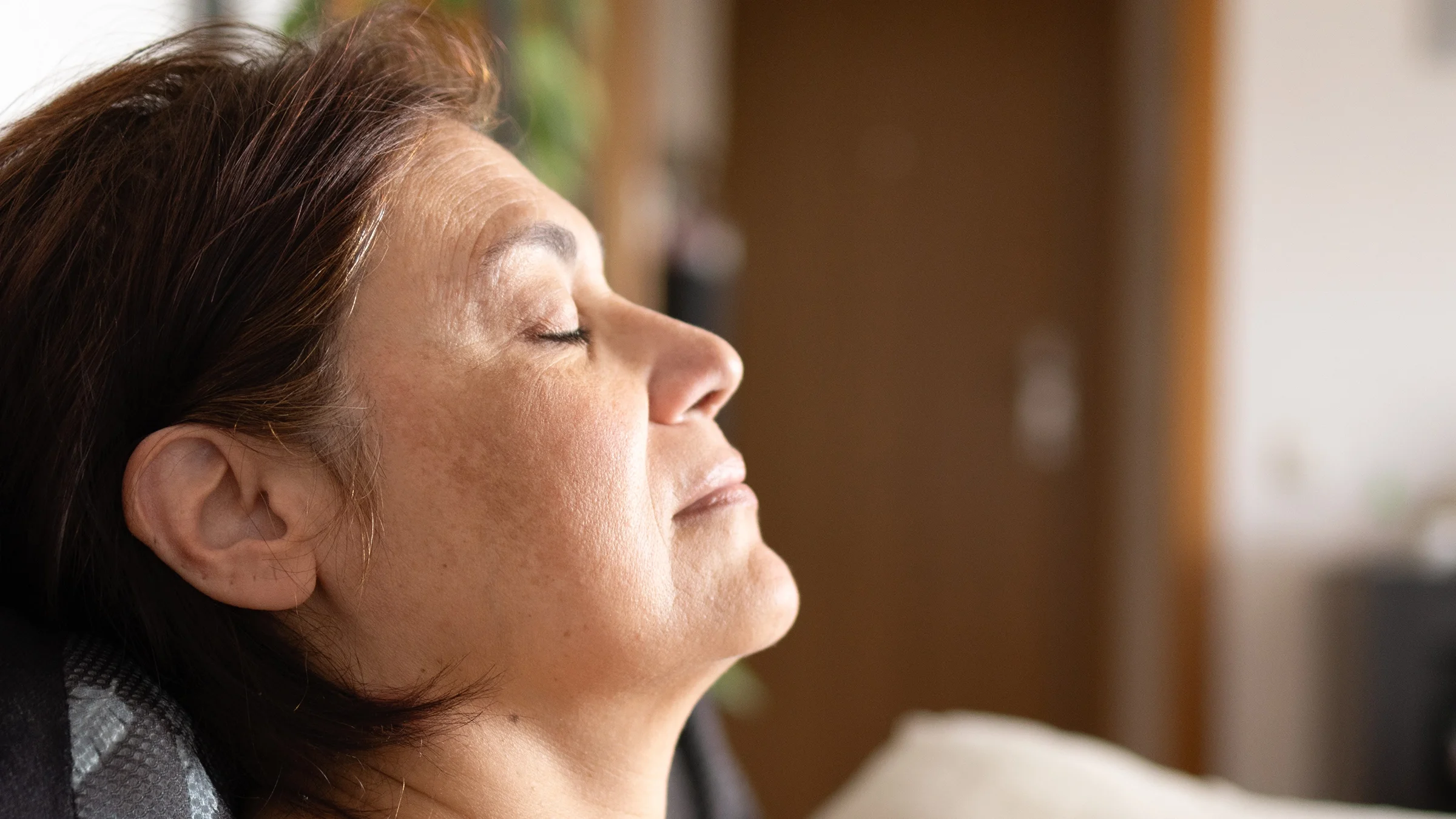 A woman rests her head with her eyes closed. 