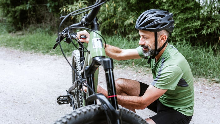 Man adjusting the seat of his mountain bike.