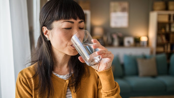 A woman is drinking a glass of water in a close-up.