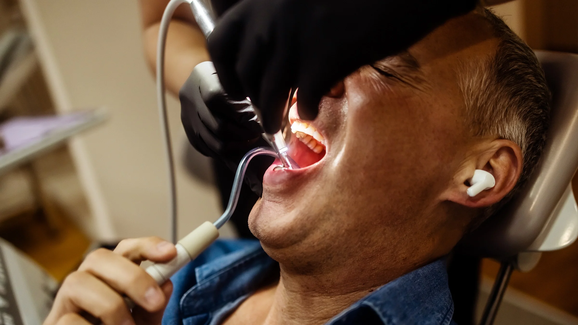 A man wears earbuds while he gets a dental cleaning.