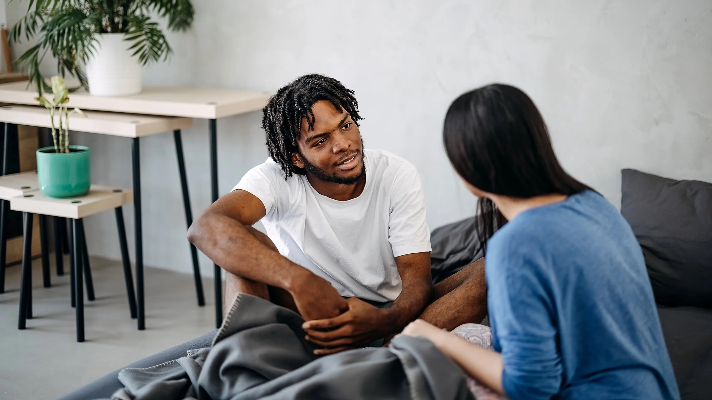 A couple sit in bed talking. For men, understanding a woman’s period can help their partners and relationship.