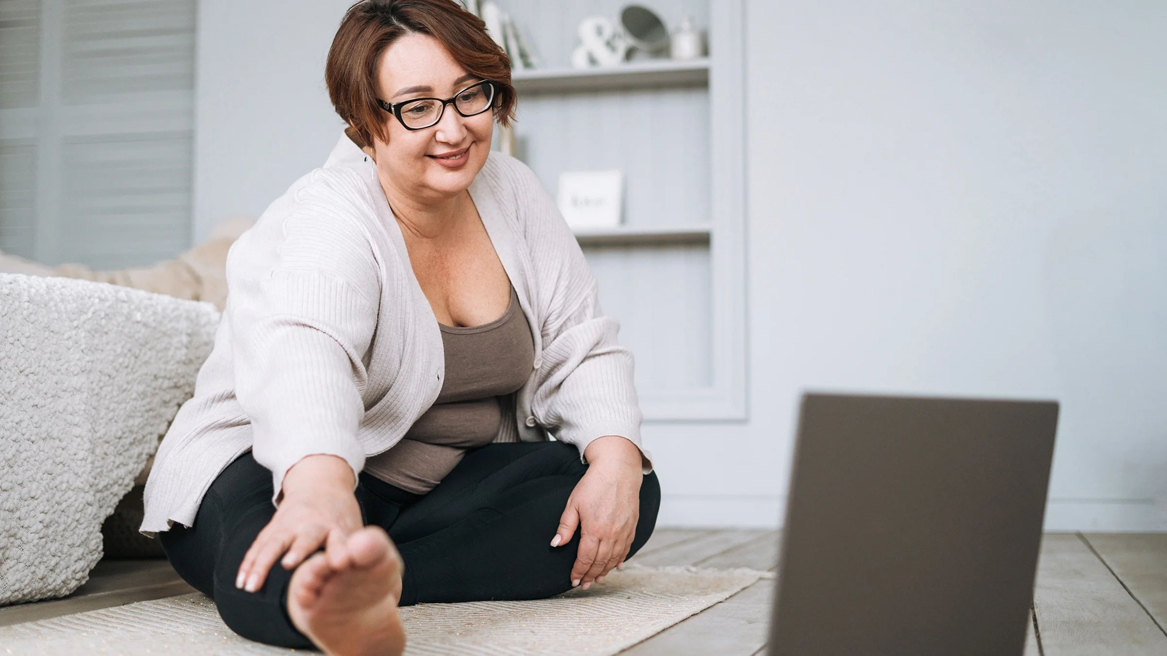 A woman does an online workout at home.
