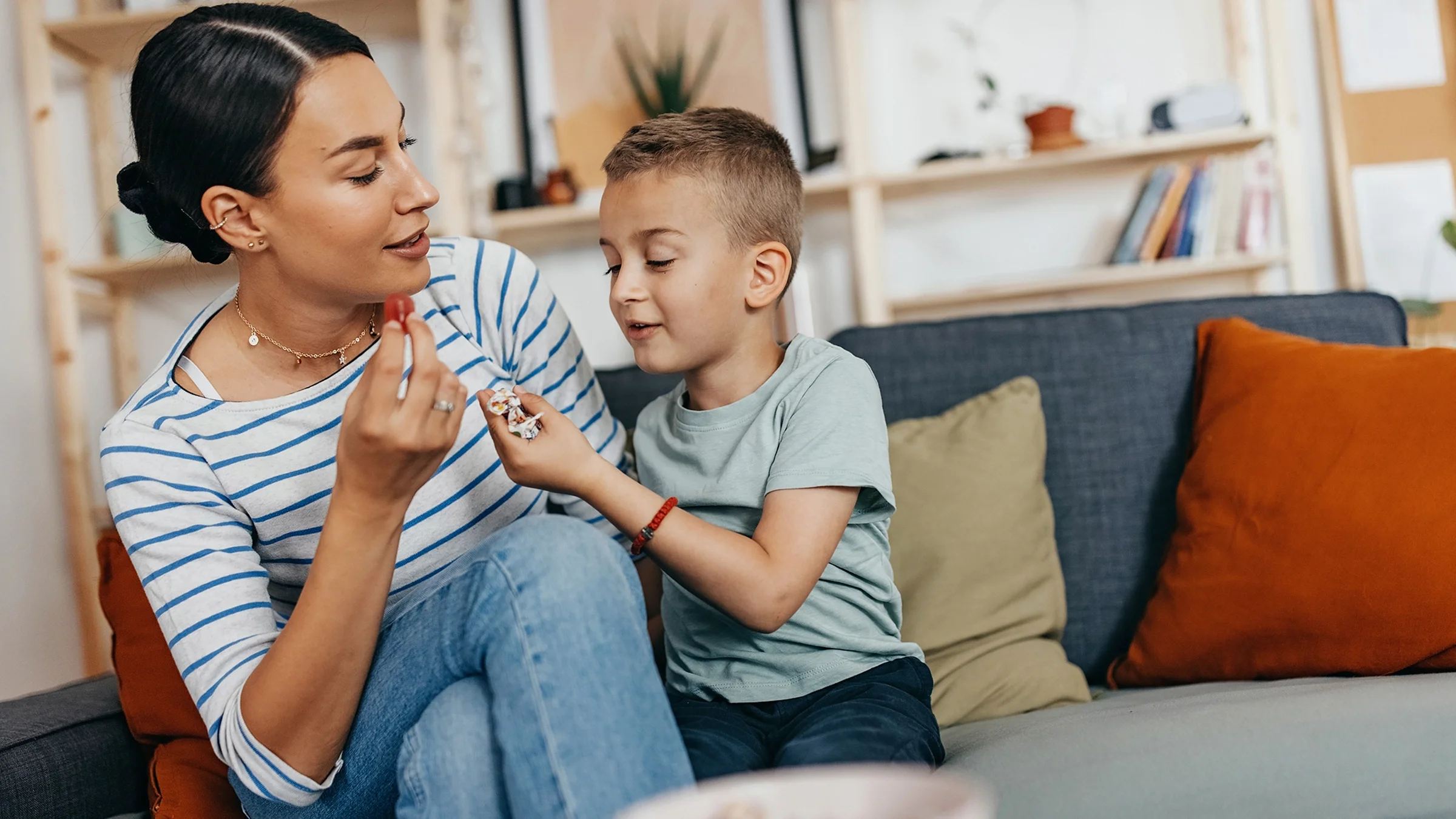 A woman and a boy eat candy while sitting on a couch.