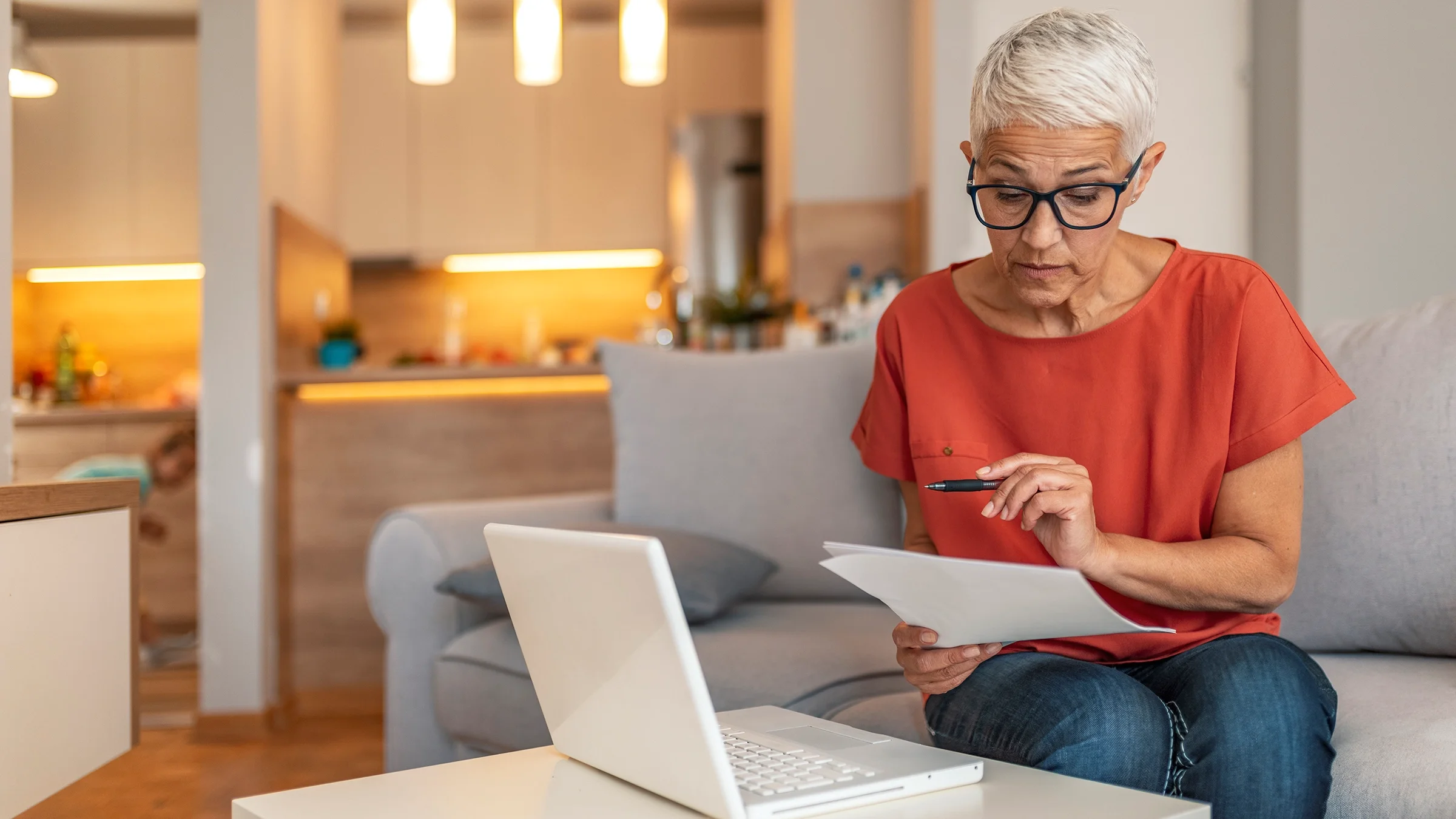 Woman reviewing documents with her laptop next to her.