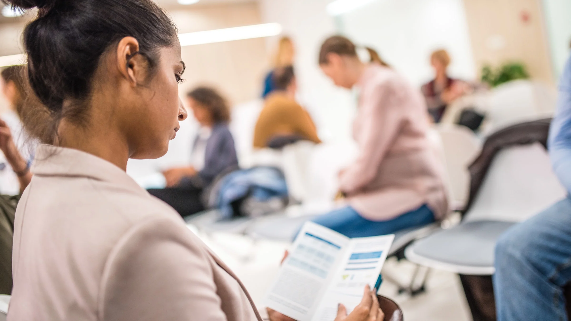 A woman reviewing a brochure in a hospital waiting room.