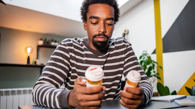Pharmacy: man reading Rx bottles 1449180440