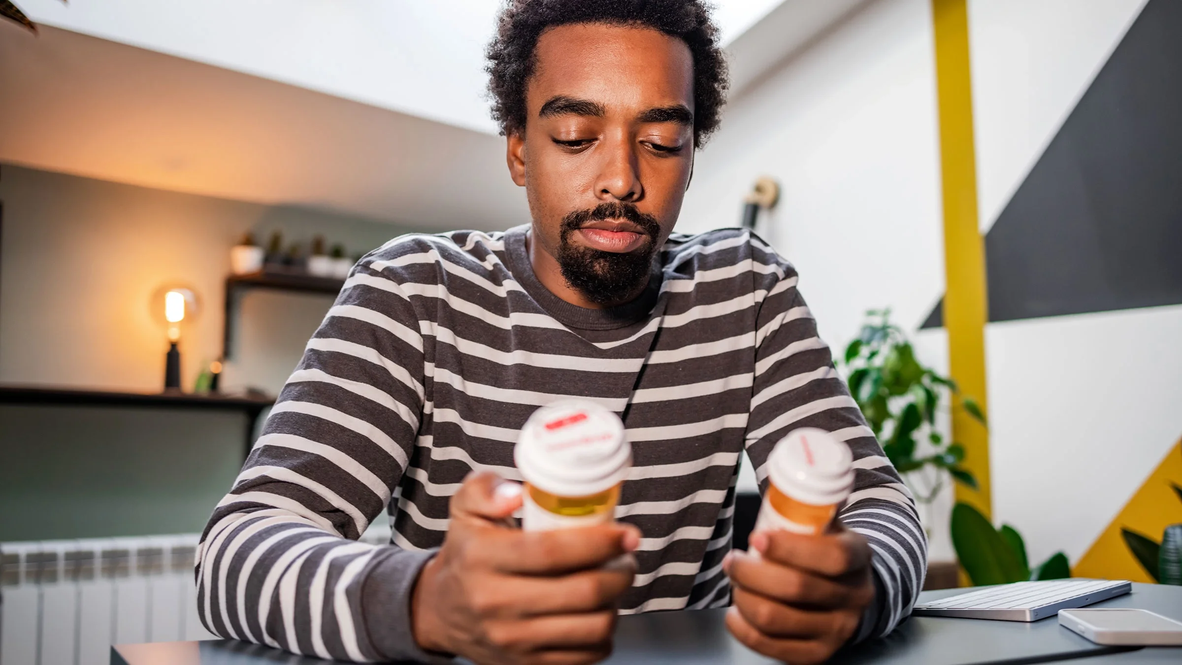 A man is reading the labels of two pill bottles.