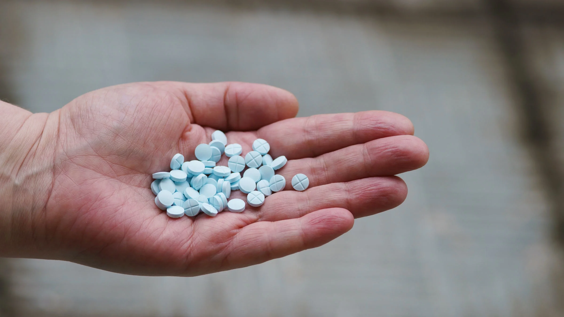 Handful of blue pills in man's hand