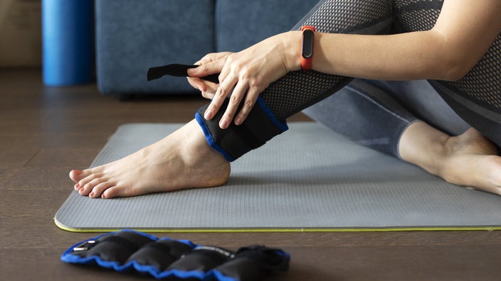 Shown is a close-up of a woman putting on ankle weights.