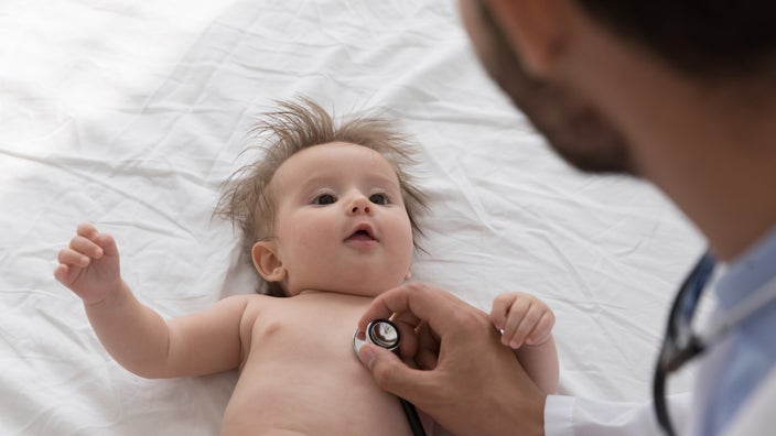 A cropped out doctor listening to a baby's heartbeat with a stethoscope.