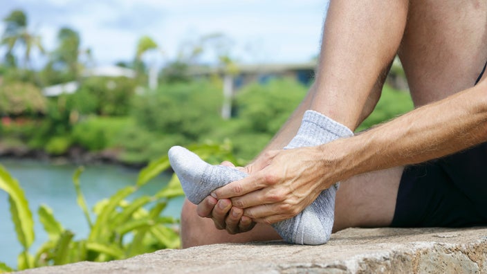 A person holding their foot in pain and stretching it.