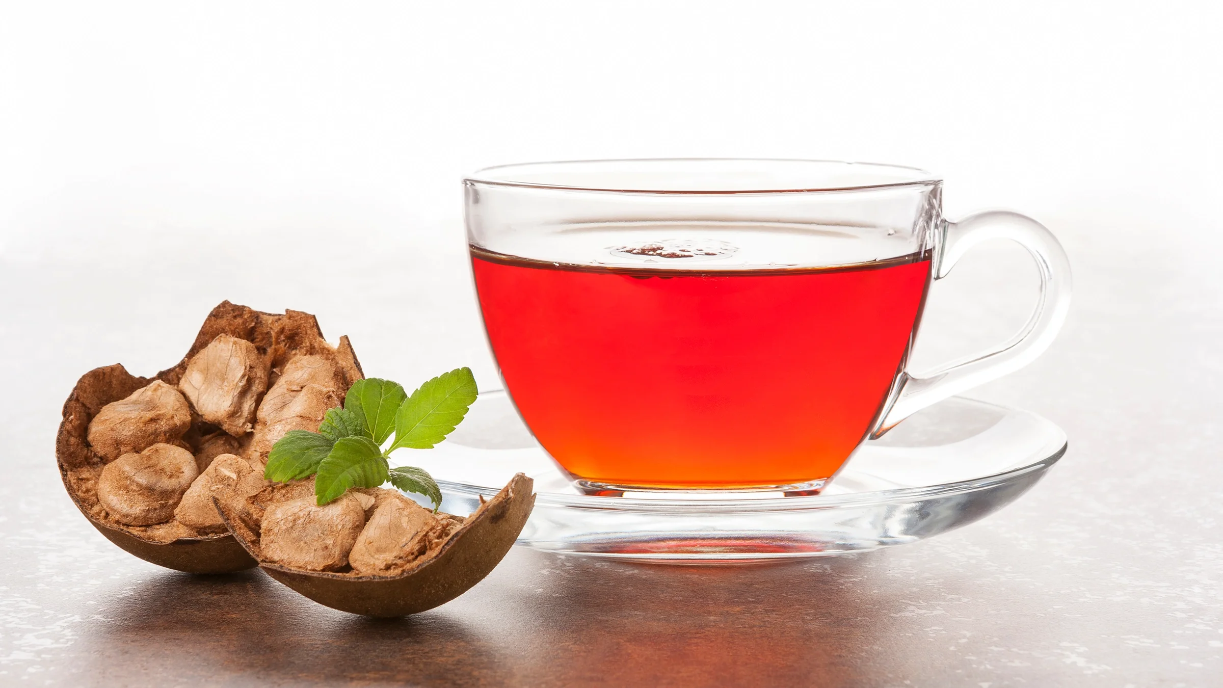 A monk fruit sits next to a cup of tea on a countertop.