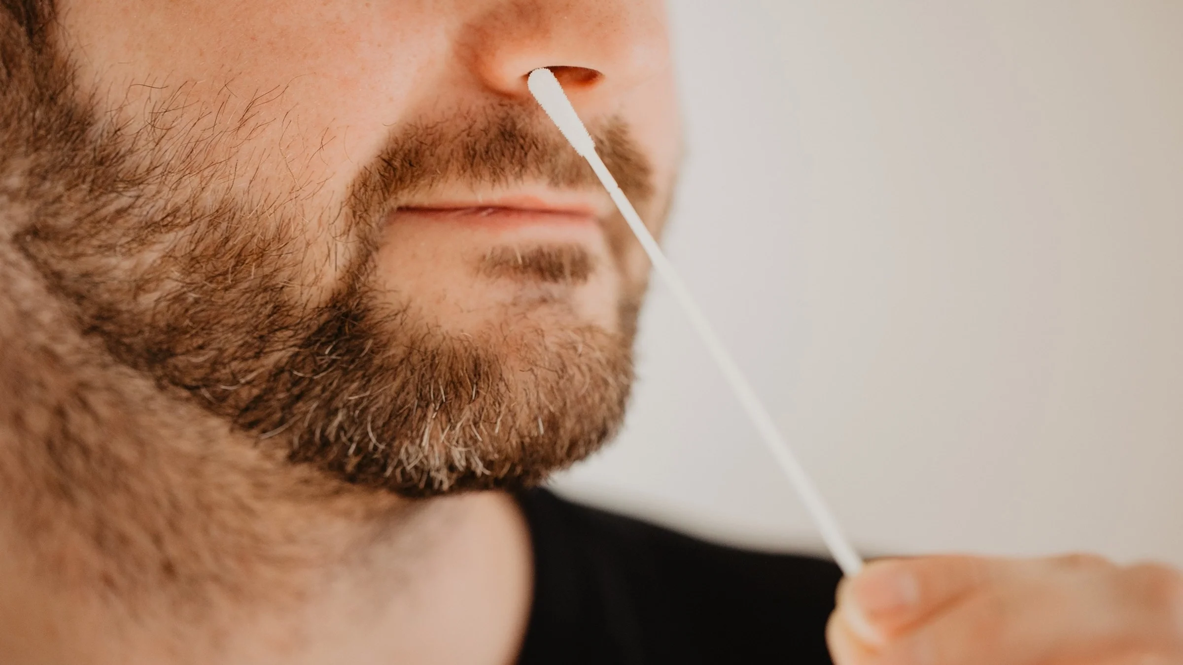 Close-up cropped shot on a man who is using a nasal swap to test for COVID-19.